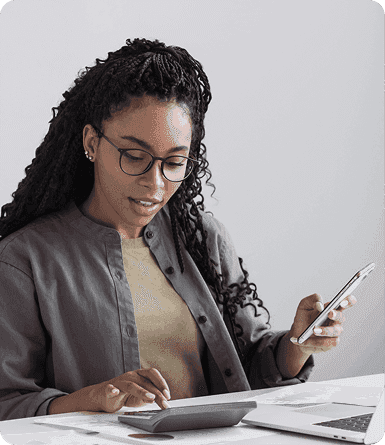 A person checks paper documents with a laptop in front of them.